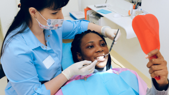 uma dentista examinando o dente de uma mulher