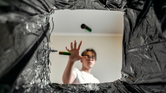 Mulher jogando duas pilhas na lixeira