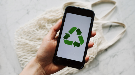 Imagem de uma mão segurando o celular com o símbolo de sustentabilidade