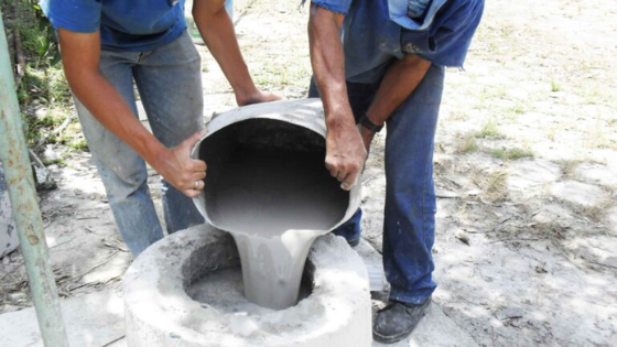 Dois homens colocando cimento em um poço